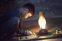 Child working by lantern light